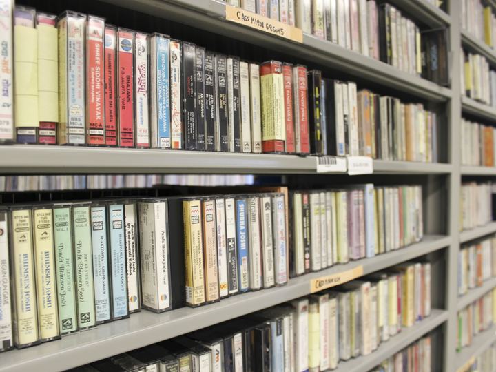 Library shelves packed with rows of audio cassette tapes in their plastic cases