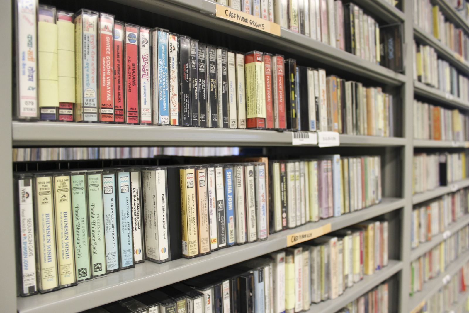 Library shelves packed with rows of audio cassette tapes in their plastic cases